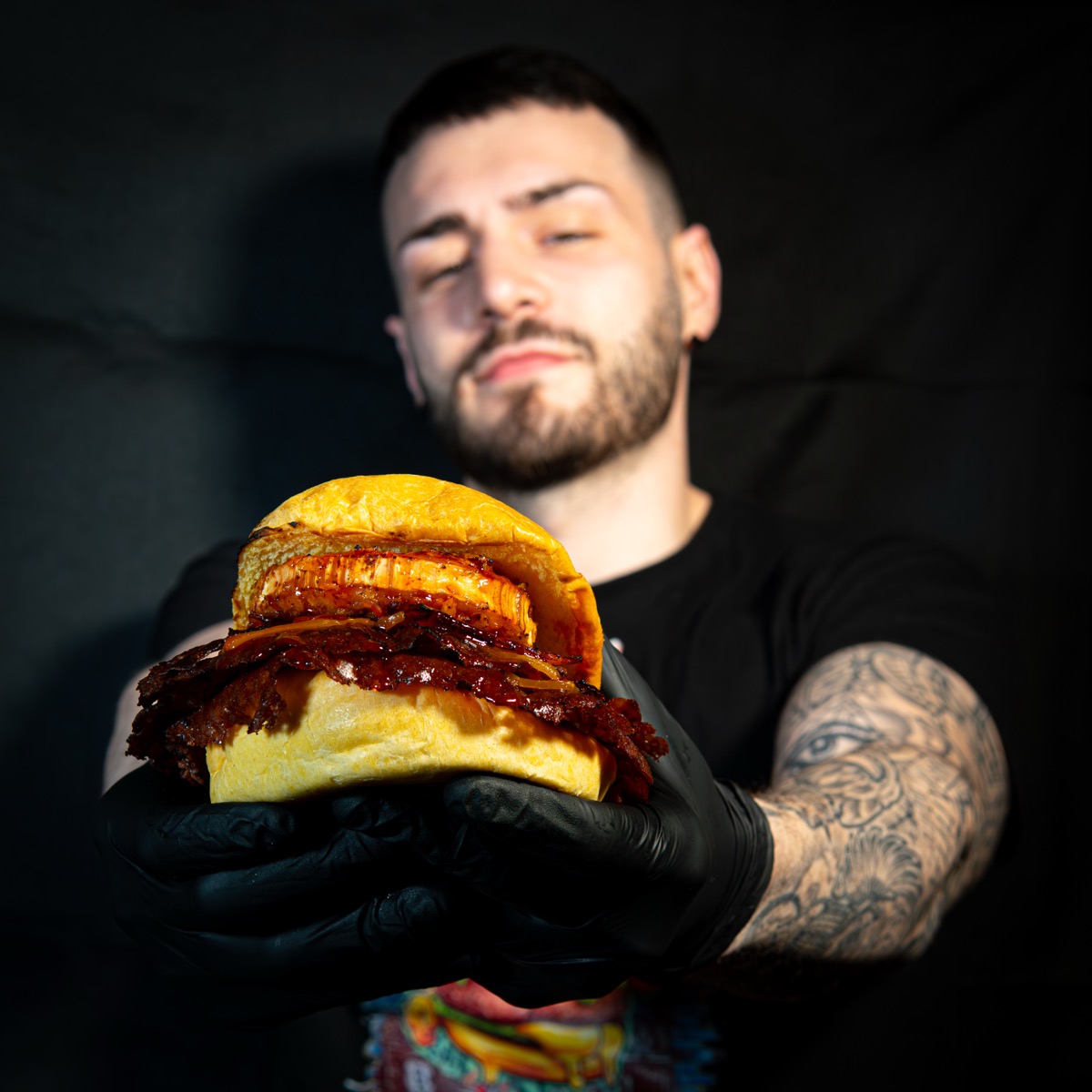 Hamburguesa D&M presentada con guantes negros